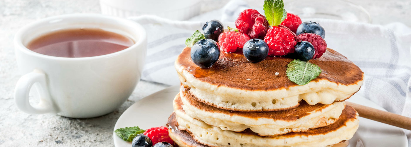 A stack of pancakes with raspberries, blueberries and mint on top