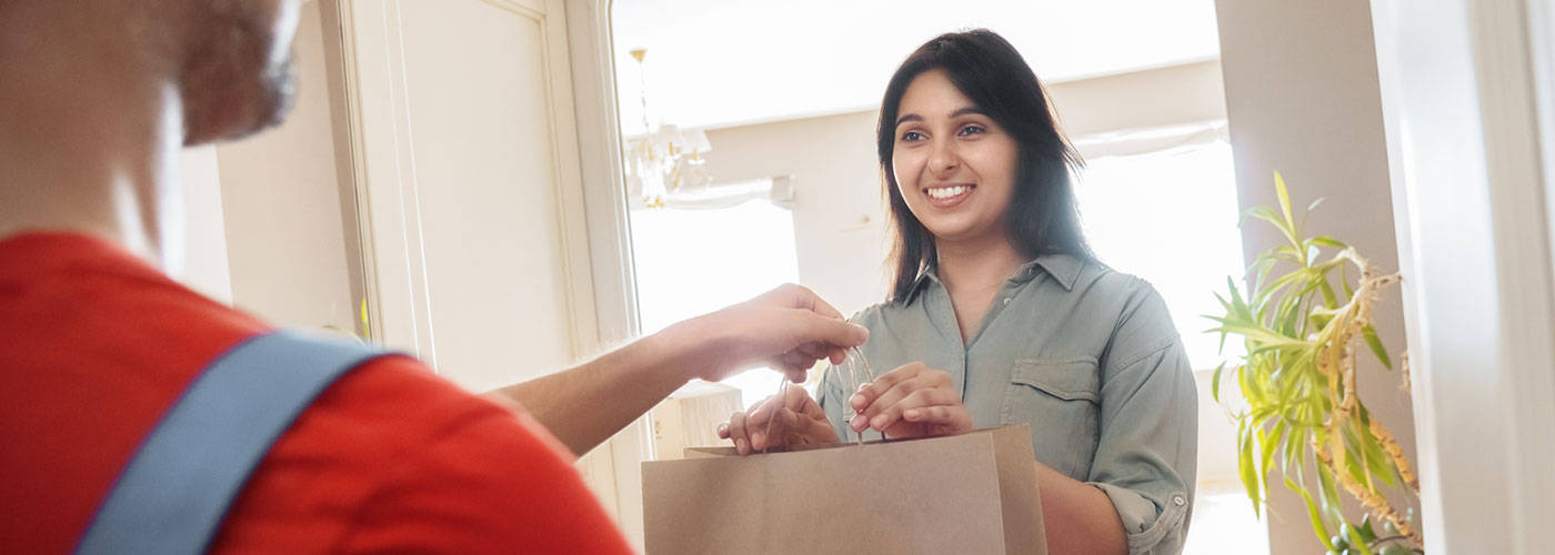 A woman grabbing a paper bag from another person