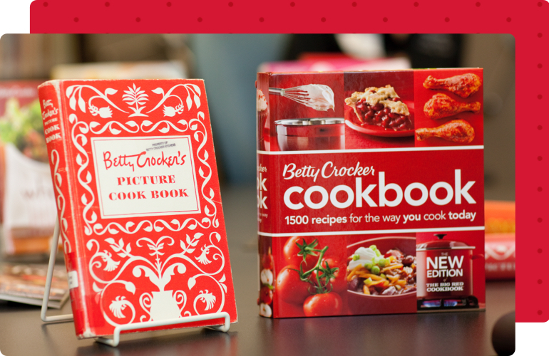 Two Betty Crocker cookbooks. One on a book stand and the other standing alone