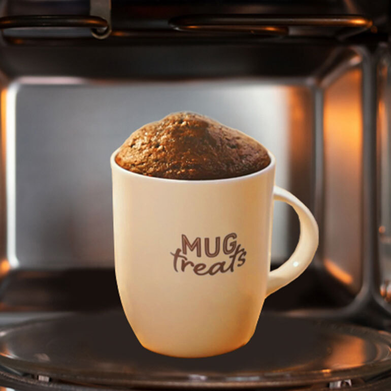 A white mug in a microwave with text on the mug saying "Mug Treats"