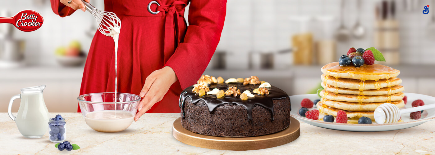 Chocolate cake on the counter with woman in the background baking