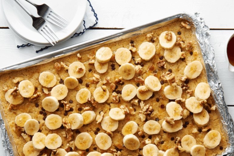 A plate of Banana Chocolate Chip Sheet Pancake with silver fork and banana slices on top