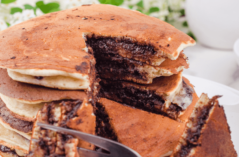 A plate of a Chocolate Spread Filled Pancakes and a slice taken out by a fork