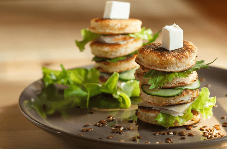 A plate of a Pancakes Sandwiches with lettuce in the middle and cheese one top