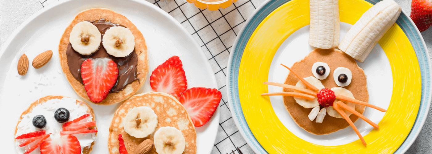 Pancakes decorated to look like animals using bananas, strawberries, carrots and blueberries